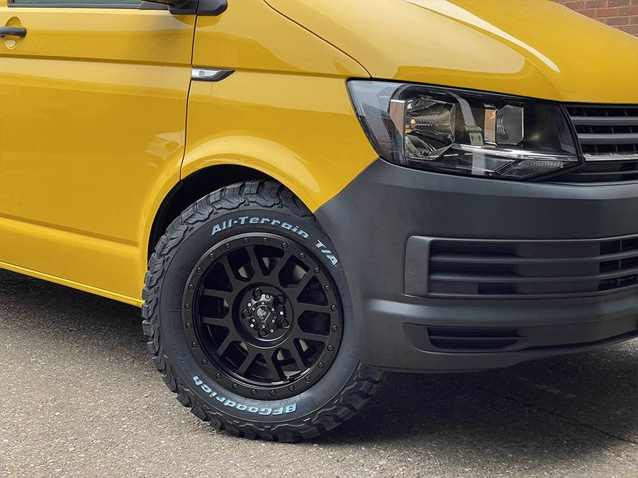 Close up of an all-terrain tyre on a yellow Transporter van